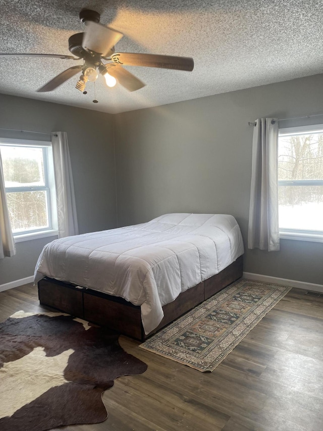 bedroom featuring a textured ceiling, wood finished floors, and baseboards