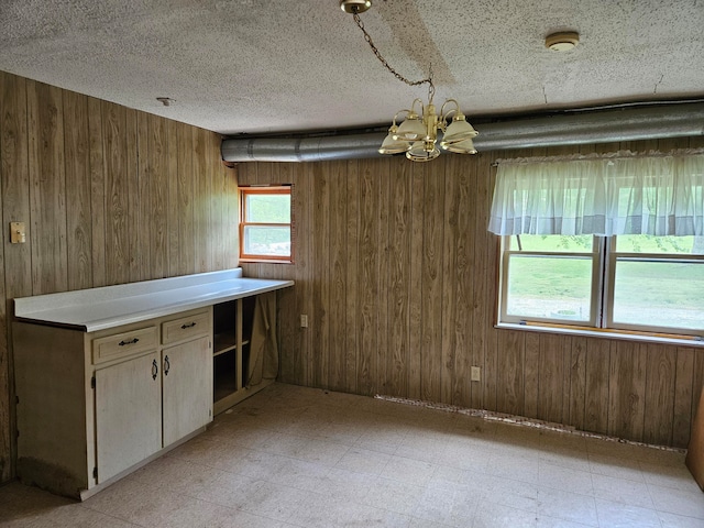 kitchen featuring wood walls, an inviting chandelier, and a textured ceiling