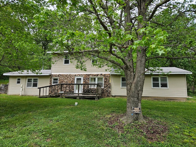 rear view of property featuring a lawn and a deck