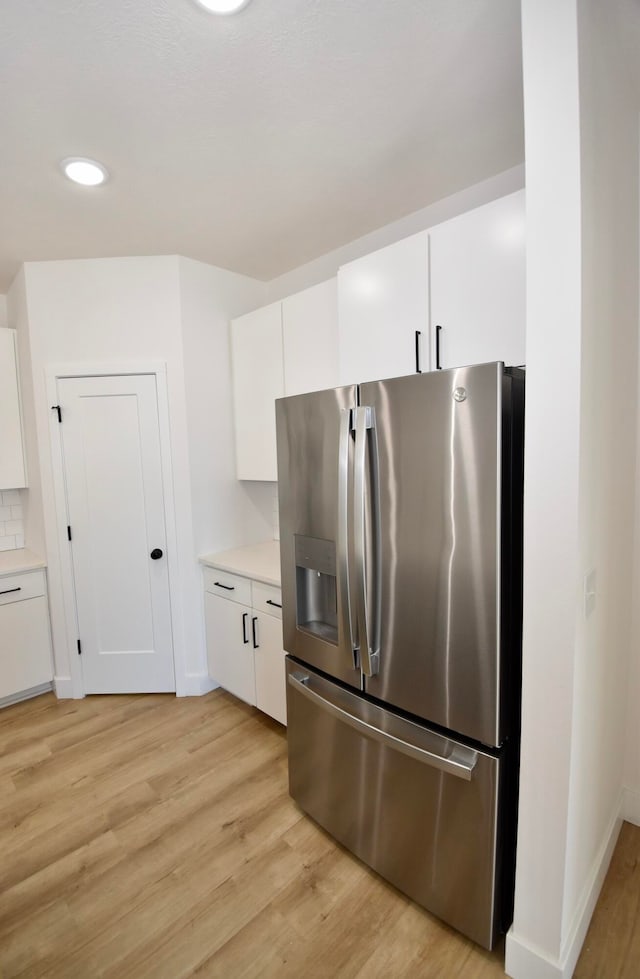 kitchen featuring light wood-type flooring, stainless steel fridge, and white cabinetry