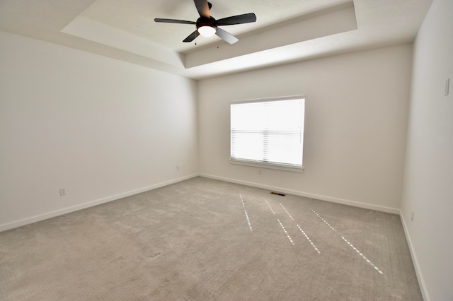 carpeted empty room featuring ceiling fan and a tray ceiling