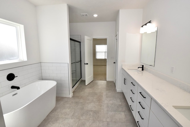 bathroom featuring tile patterned flooring, tile walls, vanity, and shower with separate bathtub