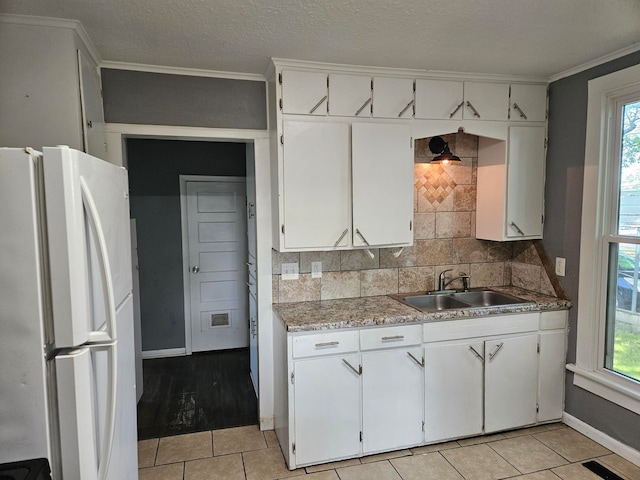 kitchen with tasteful backsplash, white fridge, sink, and white cabinets