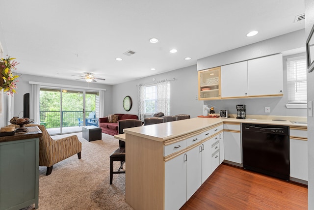 kitchen with black dishwasher, light wood-type flooring, kitchen peninsula, and white cabinetry