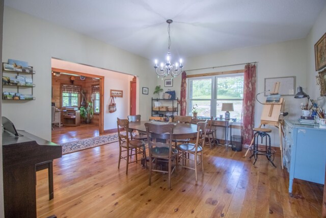 dining area with a healthy amount of sunlight, light hardwood / wood-style flooring, and an inviting chandelier