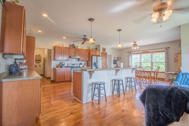 kitchen featuring stainless steel appliances, light wood-type flooring, a kitchen breakfast bar, and hanging light fixtures