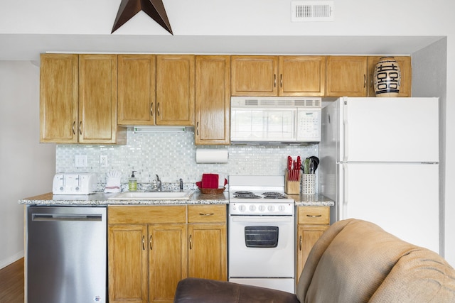 kitchen featuring light stone counters, sink, white appliances, backsplash, and dark wood-type flooring