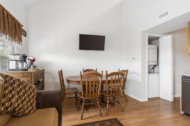 dining space featuring light hardwood / wood-style flooring and stacked washer and dryer