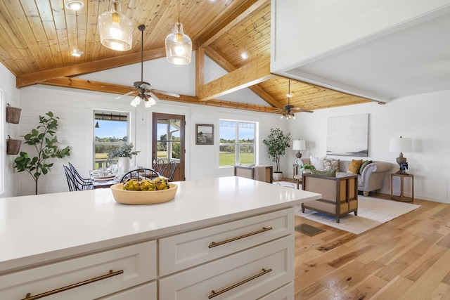 kitchen featuring vaulted ceiling with beams, white cabinets, decorative light fixtures, wooden ceiling, and light hardwood / wood-style floors