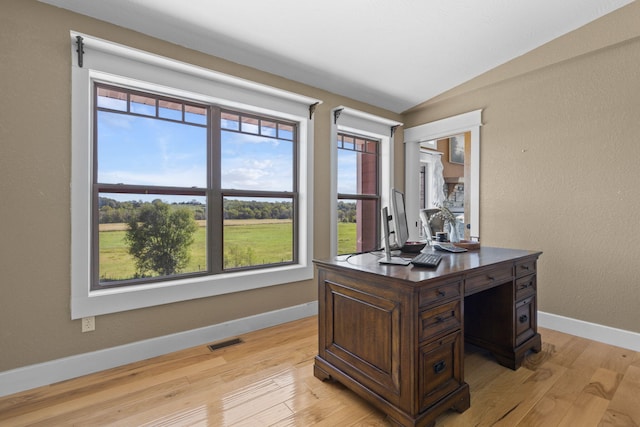 office space with vaulted ceiling and light hardwood / wood-style flooring