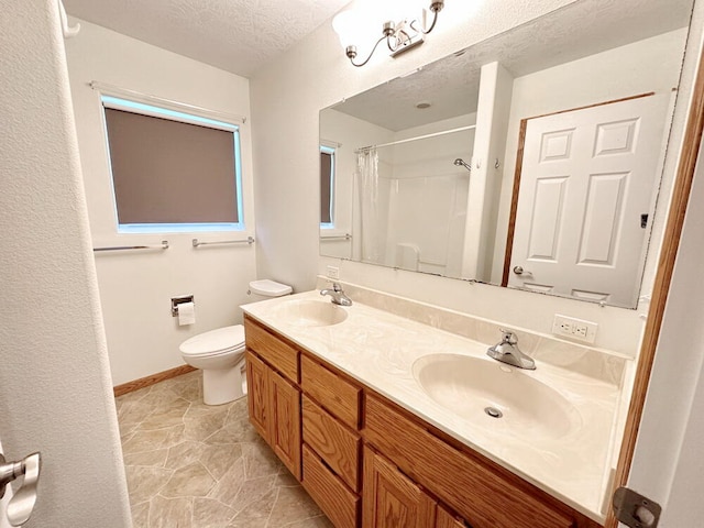 bathroom with vanity, toilet, curtained shower, and a textured ceiling