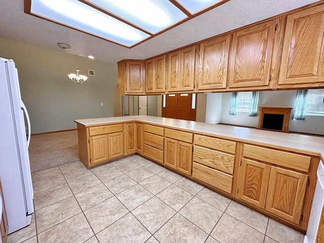 kitchen with a chandelier, light tile patterned floors, light countertops, a peninsula, and freestanding refrigerator