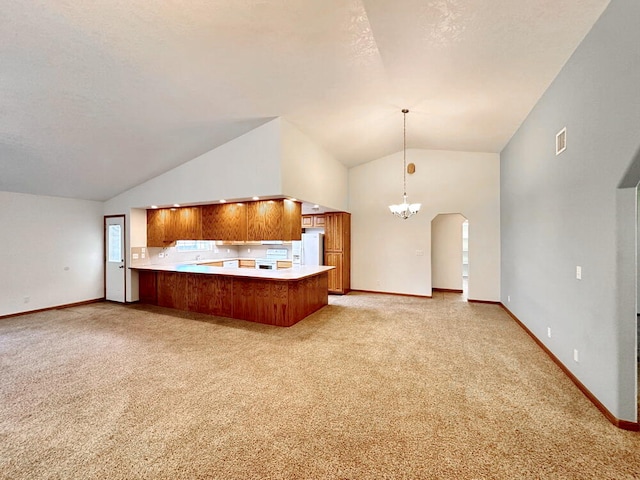 kitchen featuring white refrigerator with ice dispenser, pendant lighting, light colored carpet, a notable chandelier, and kitchen peninsula