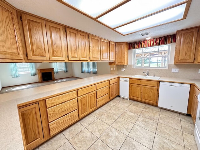 kitchen with kitchen peninsula, sink, light tile patterned floors, and dishwasher