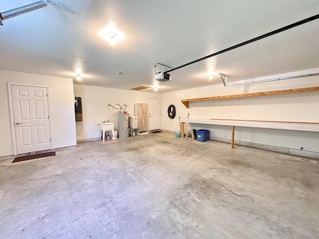 garage with water heater, a garage door opener, and a sink