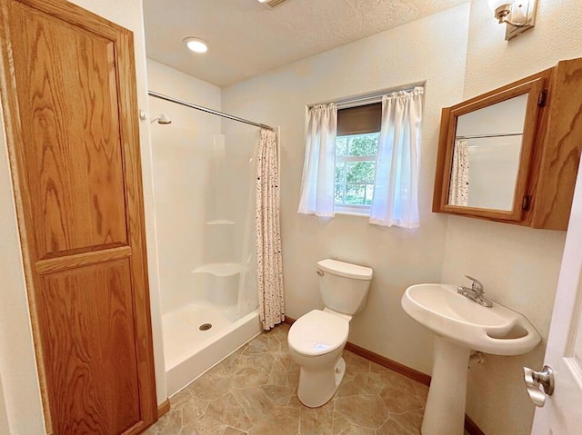 full bathroom featuring tile patterned floors, a sink, a stall shower, toilet, and baseboards