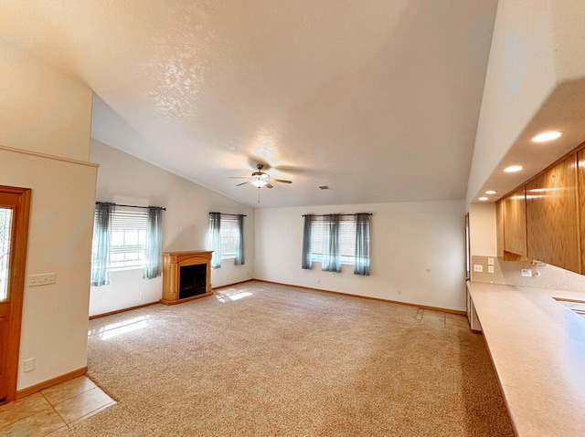 unfurnished living room with light carpet, a healthy amount of sunlight, ceiling fan, and lofted ceiling