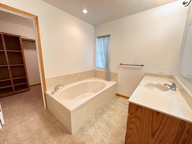 bathroom featuring a jetted tub, vanity, a walk in closet, baseboards, and a textured ceiling