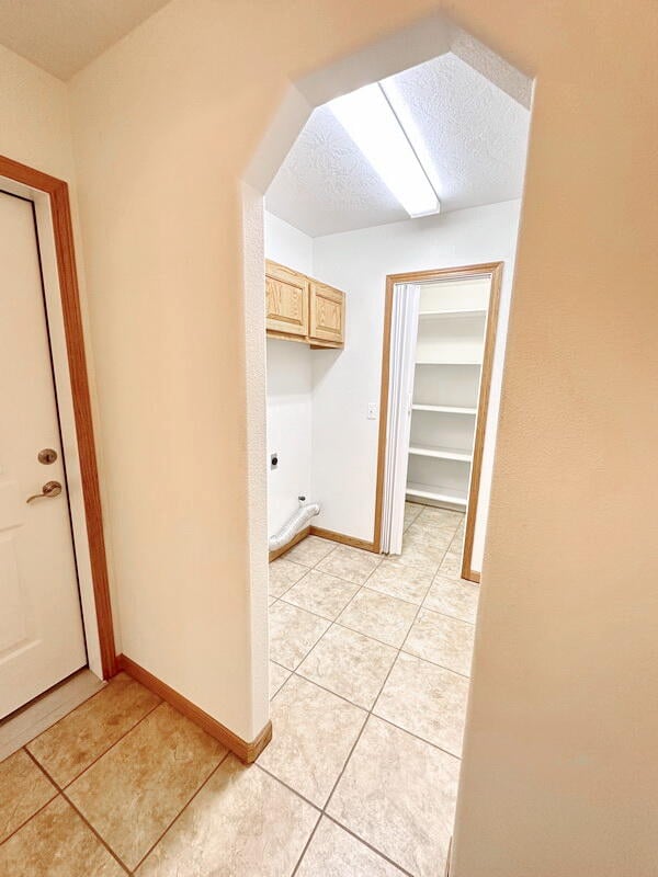 laundry room featuring hookup for an electric dryer, a skylight, light tile patterned floors, and a textured ceiling