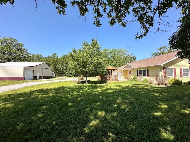 view of yard featuring gravel driveway, an outdoor structure, an outbuilding, and a detached garage