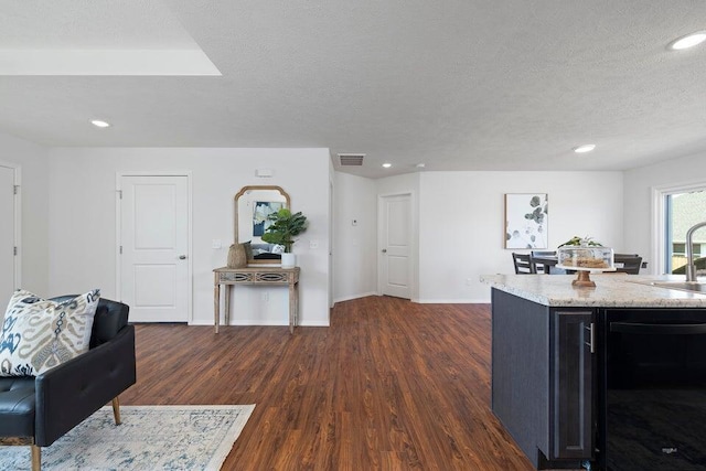 kitchen with light stone counters, sink, a textured ceiling, dark wood-type flooring, and dishwasher