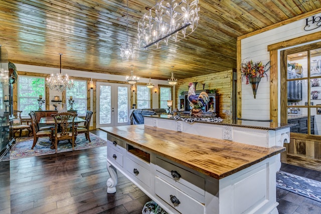 kitchen featuring white cabinets, wood walls, wooden counters, french doors, and a center island