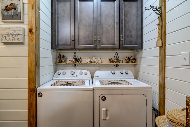 laundry area with cabinets, wooden walls, and washing machine and dryer