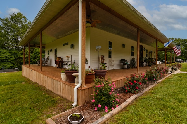 exterior space featuring a wooden deck, ceiling fan, and a lawn