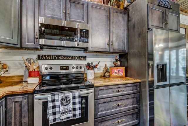 kitchen with dark brown cabinetry, appliances with stainless steel finishes, backsplash, and wooden counters