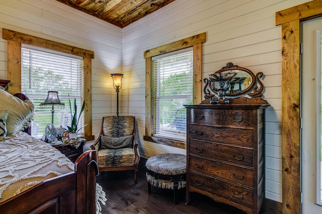 bedroom with wooden walls, wood ceiling, dark hardwood / wood-style floors, and multiple windows