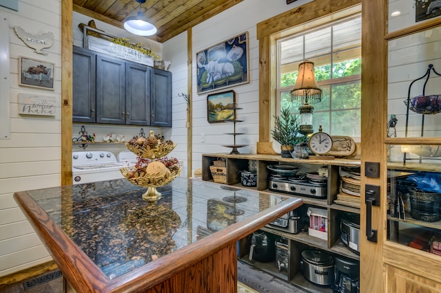 interior space featuring wood ceiling, wood walls, independent washer and dryer, and a center island