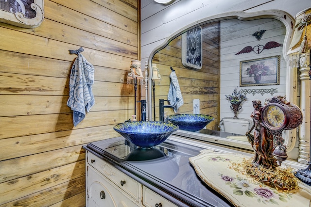 bathroom with wood walls, vanity, and toilet