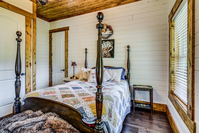 bedroom with dark wood-type flooring, wood ceiling, and wooden walls