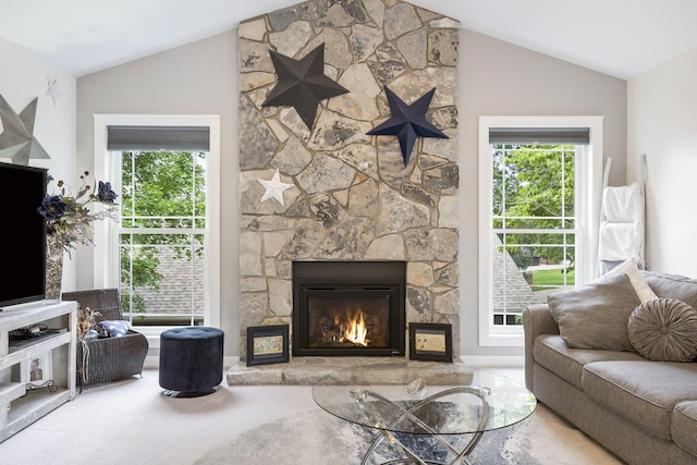 carpeted living room with a stone fireplace and vaulted ceiling