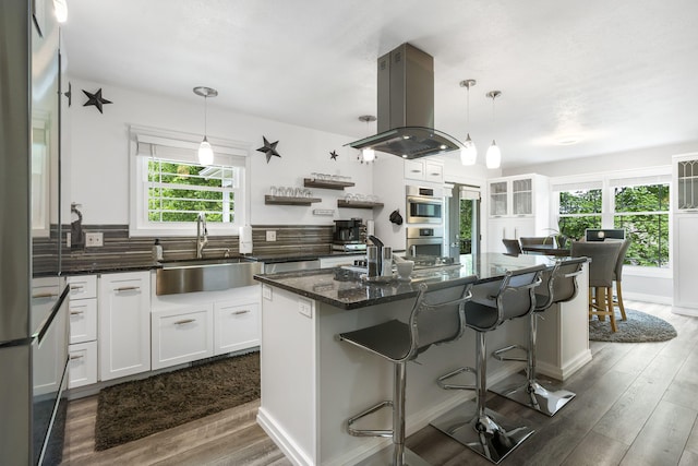 kitchen with dark hardwood / wood-style flooring, island range hood, sink, white cabinets, and a kitchen island