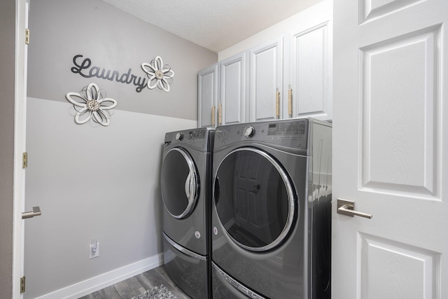 laundry area featuring washing machine and clothes dryer, hardwood / wood-style floors, cabinets, and a textured ceiling