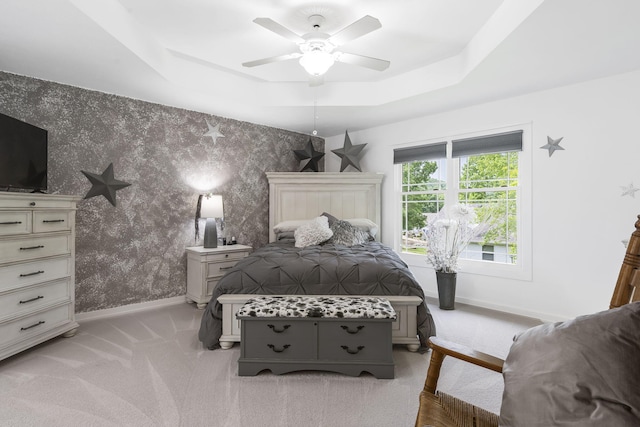 carpeted bedroom featuring ceiling fan and a tray ceiling