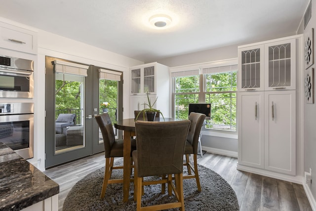 dining room featuring a textured ceiling, light hardwood / wood-style flooring, and french doors