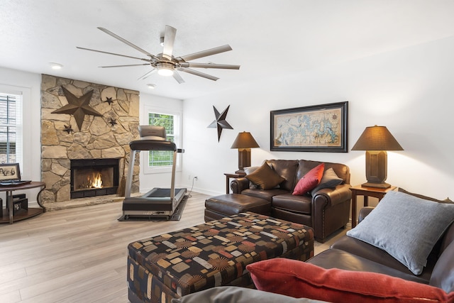 living room featuring a fireplace, light hardwood / wood-style flooring, and ceiling fan