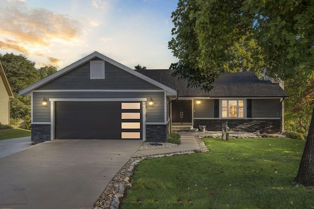 view of front of property with stone siding, a lawn, driveway, and an attached garage