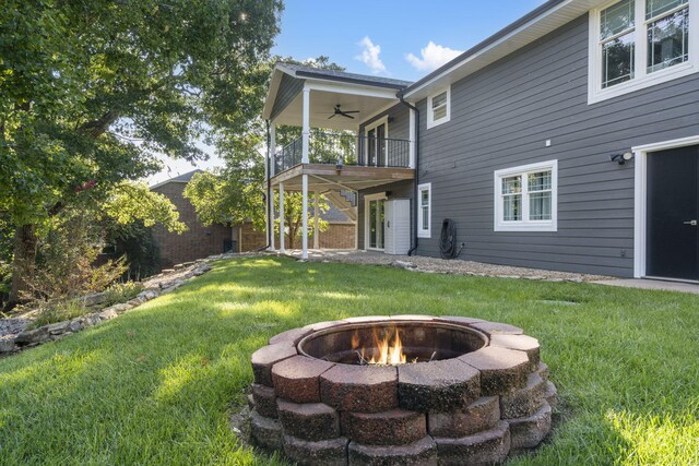 view of yard featuring ceiling fan, a balcony, and an outdoor fire pit