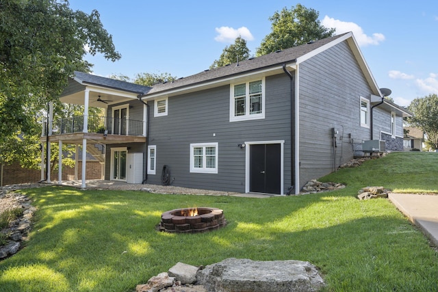 back of property featuring a balcony, a deck, ceiling fan, an outdoor fire pit, and a yard