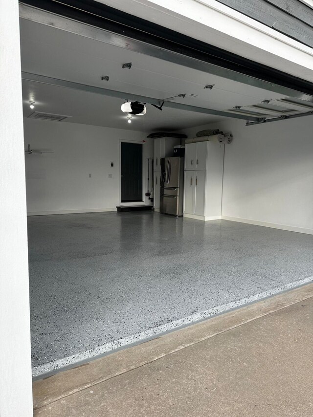 garage with stainless steel fridge with ice dispenser and a garage door opener