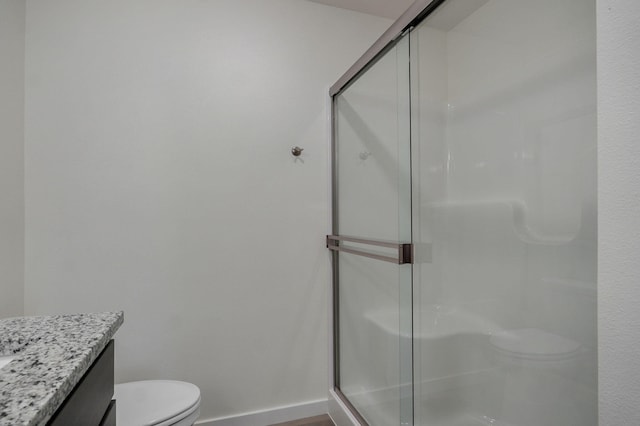 bathroom featuring vanity, toilet, and a shower with shower door