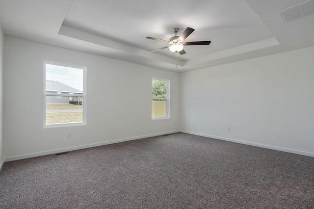 spare room featuring carpet flooring, ceiling fan, and a raised ceiling