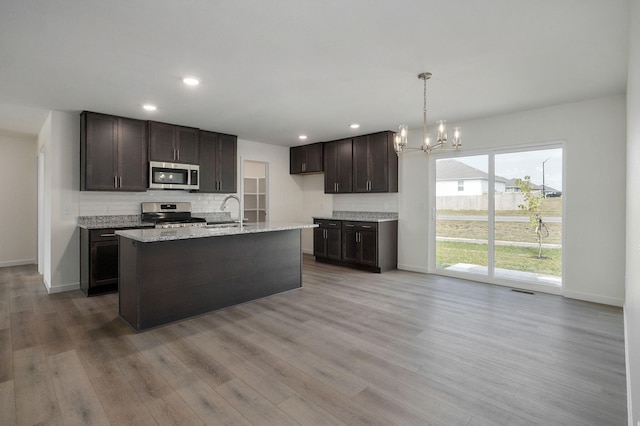 kitchen featuring appliances with stainless steel finishes, decorative light fixtures, a chandelier, and light hardwood / wood-style flooring