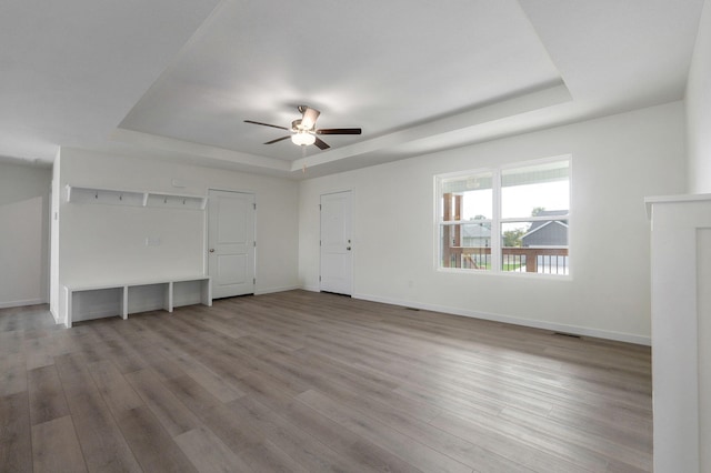 unfurnished living room featuring ceiling fan, hardwood / wood-style floors, and a raised ceiling