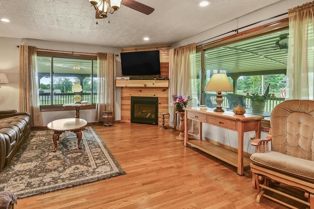 living area featuring a textured ceiling, recessed lighting, wood finished floors, ceiling fan, and a fireplace