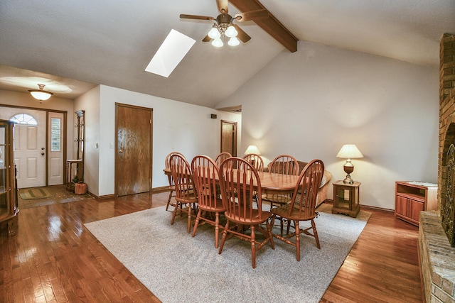dining room featuring lofted ceiling with skylight, wood finished floors, a ceiling fan, and baseboards