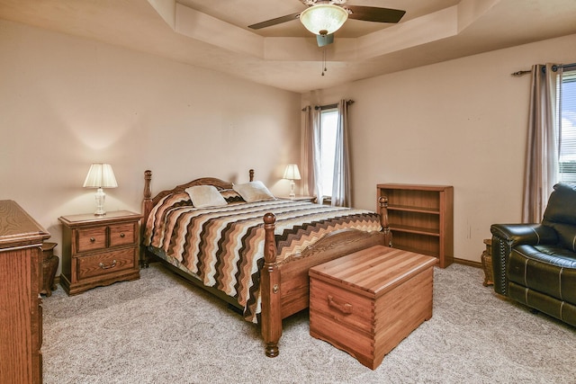 bedroom featuring a tray ceiling, carpet flooring, baseboards, and a ceiling fan